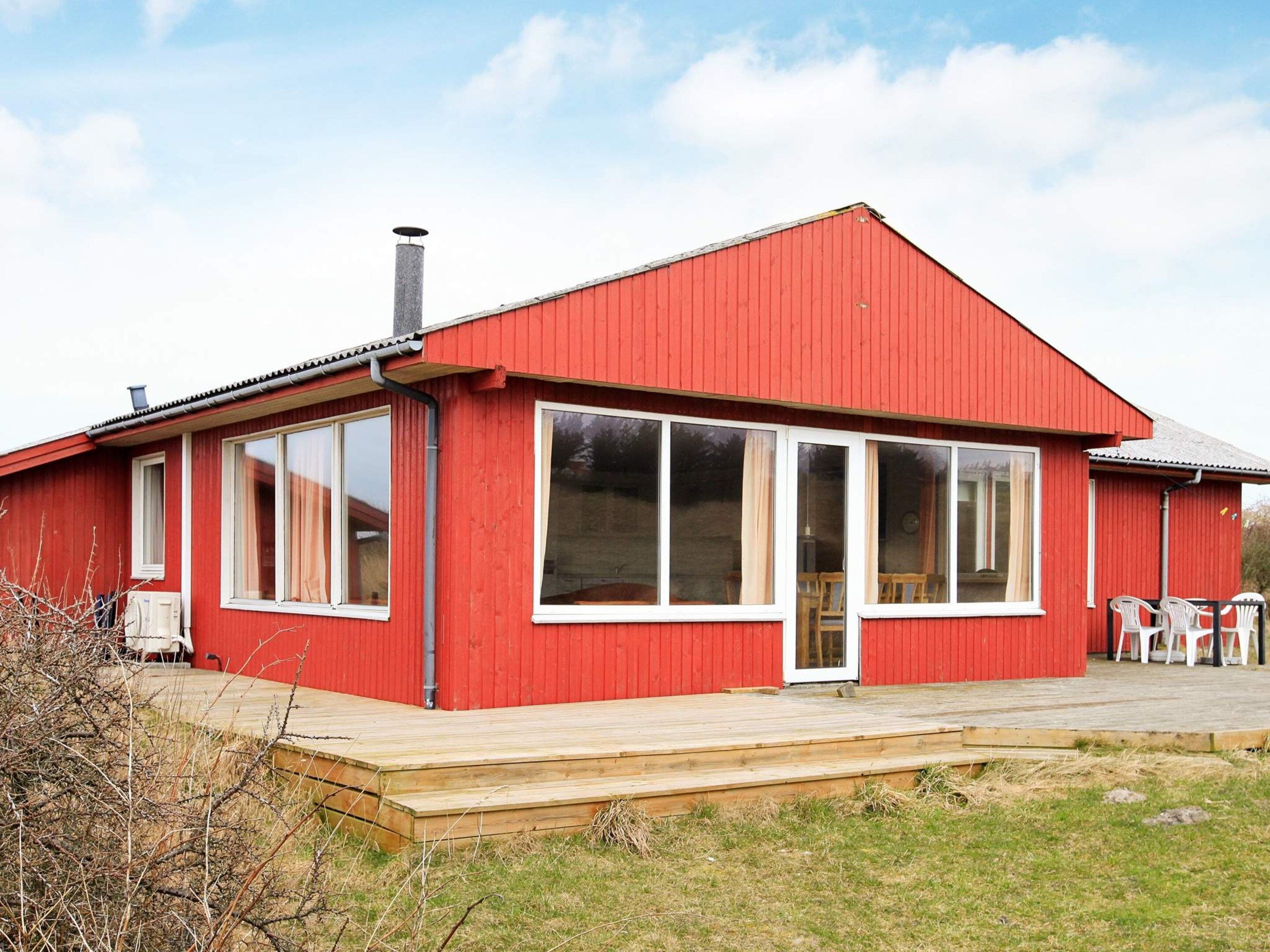 Et rødt, etetages hus med en stor veranda og skorsten.