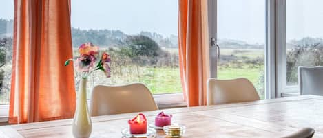 Un comedor con una mesa, sillas, un jarrón con flores y velas.