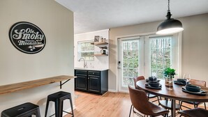 A modern kitchen with black cabinets, a wooden countertop, and a dining area with a round table and chairs.