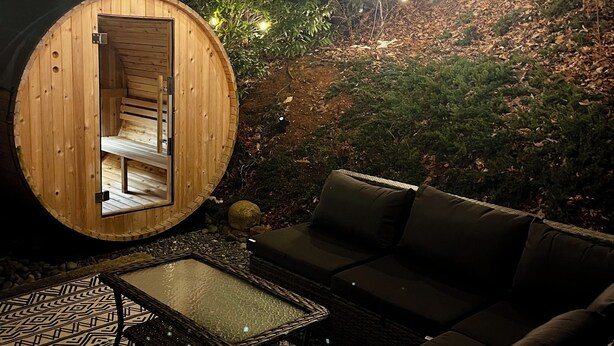 A wooden cabin with a glass door, a sofa, and a patterned table.