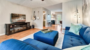 A living room with a blue sofa, a television, and a ceiling fan.