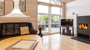 Ein modernes Wohnzimmer mit einer Ledersofa, einem Holztisch, einem Kamin und einem Fernseher auf einem Lowboard.