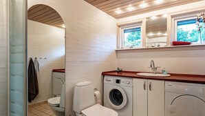 A compact bathroom with a washing machine, a toilet, and a sink. - 6 Person Holiday Home in Hals (Hals)