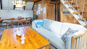 A cozy cabin interior with a wooden dining table, a sofa, and a staircase. - 6 Person Holiday Home in Hals-by Traum (Hals)