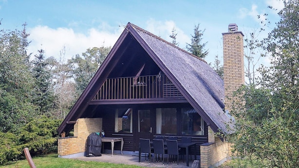 A cabin with a sloped roof, a balcony, a patio with outdoor seating, and a chimney. - 6 Person Holiday Home in Hals-by Traum (Hals)