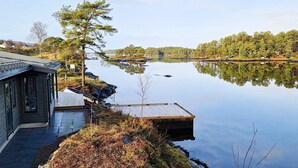 A lakeside cabin with a dock extending into the water, surrounded by trees and a clear view of the lake.