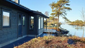 A modern house with a large window, a chimney, and a view of a lake.