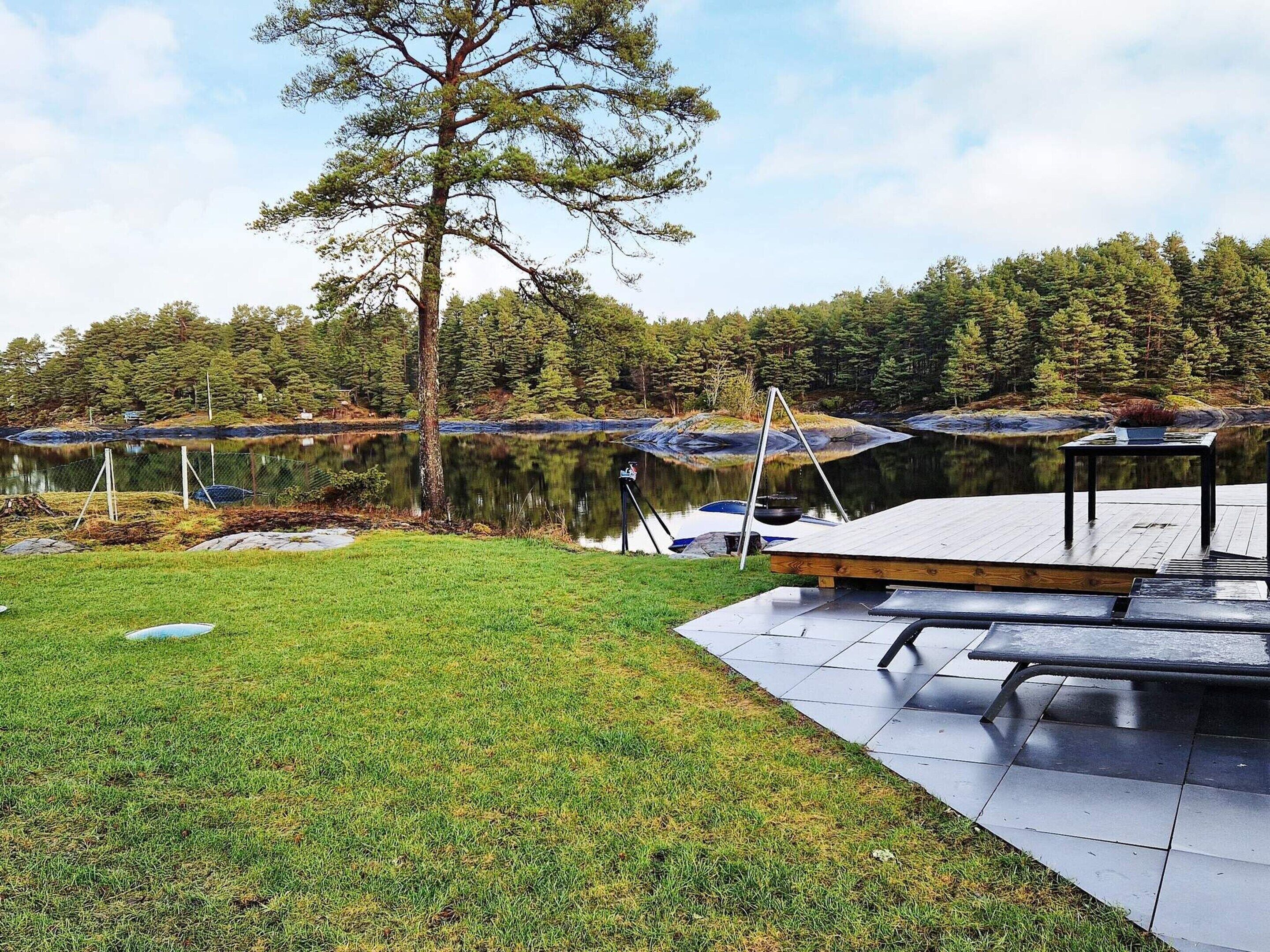 A lakeside deck with a picnic table and a grill.