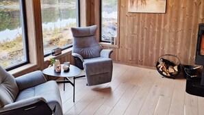 A cozy room with a large window overlooking a lake, a fireplace, and a comfortable seating area.