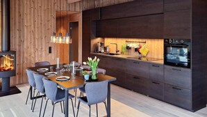 A modern kitchen with dark cabinetry, a central island, and a built-in oven.