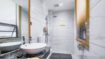 A modern bathroom with a large white sink, a glass bowl sink, a shower, and a toilet.