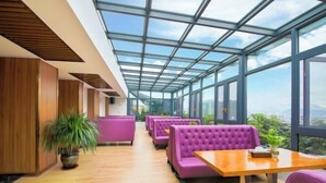 A modern interior with a glass ceiling, wooden flooring, and purple seating areas.