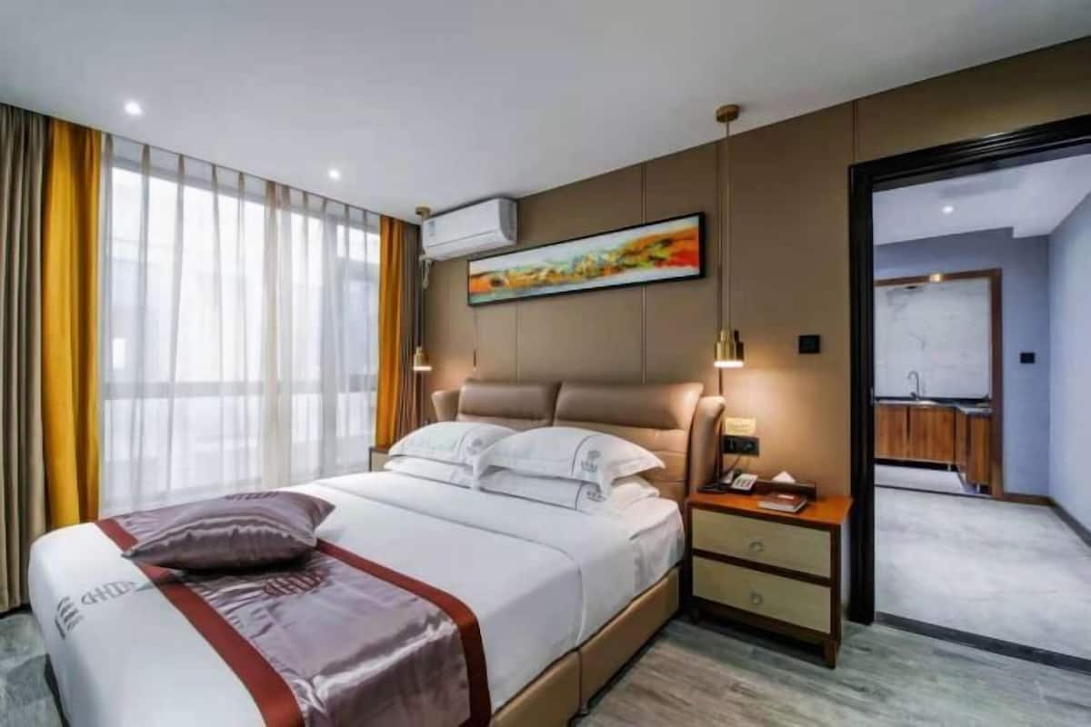 A hotel room with a bed, bedside table, and a painting on the wall.