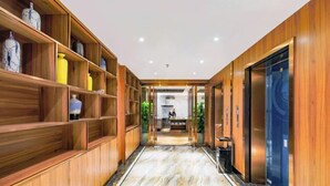 A hallway with wooden shelving, marble flooring, and an elevator.