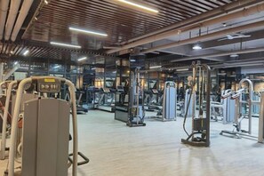 Une salle de sport équipée de divers appareils d’exercice, dotée d’un mur couvert de miroirs et d’un plancher en bois.