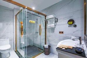 A modern bathroom with a glass-enclosed shower, a white toilet, a sink with a mirror, and a towel rack. - Huangting Hotel (Xintian)