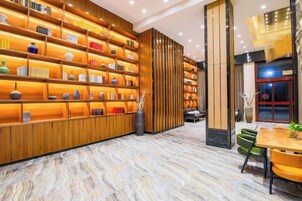 Un vestíbulo con piso de mármol, estanterías de madera con adornos, un mostrador de recepción y un área de estar con sillas.