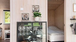 Une petite pièce comprenant un lit, une vitrine contenant des verres à vin et deux tableaux encadrés accrochés au mur.