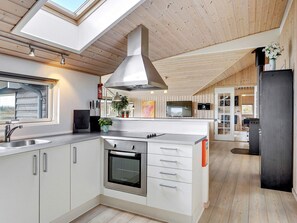 A modern kitchen with a skylight, built-in oven, and wooden cabinetry. - 10 Person Holiday Home in Lokken (Lokken)