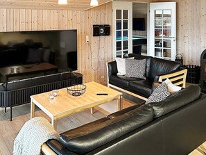 A modern living room with a black leather sofa, a wooden coffee table, and a flat-screen TV. - 10 Person Holiday Home in Lokken (Lokken)