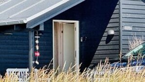 A building with a dark exterior, a visible door, and a small porch area. - 10 Person Holiday Home in Lokken (Lokken)