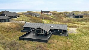 Ein Küsteneigentum mit mehreren Gebäuden, darunter ein auffälliges Haus mit einer großen Terrasse und ein kleineres Gebäude in der Nähe.