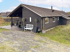 A modern building with a sloped roof, a covered porch, and a bench. - 10 Person Holiday Home in Lokken (Lokken)