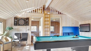 Une pièce chaleureuse équipée d’une table de billard, d’un jeu de fléchettes et d’un téléviseur.