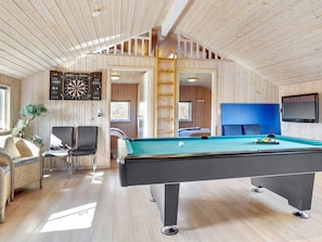 A cozy room with a pool table, a dartboard, and a television.