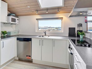 A modern kitchen with a built-in microwave, a dishwasher, and a window with a view. - 10 Person Holiday Home in Lokken (Lokken)