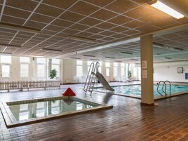 An indoor swimming pool area with a diving board, a slide, and a small pool.