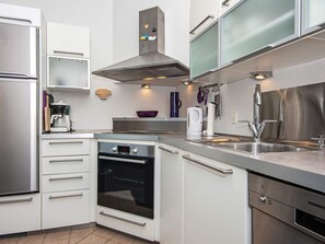 Eine moderne Küche mit weißen Schränken, Edelstahlgeräten und einem eingebauten Backofen.