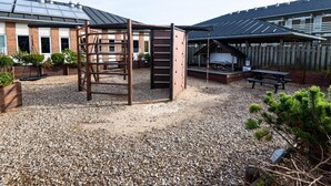 A playground with a climbing structure, a picnic table, and a covered seating area.