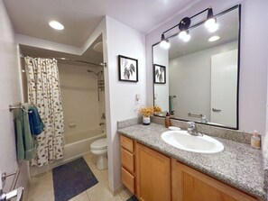 A bathroom with a shower, toilet, sink, and vanity.