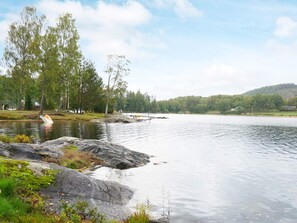 Un lac paisible avec une jetée qui s’avance sur l’eau, entouré d’arbres et bordé, au loin, par une colline.