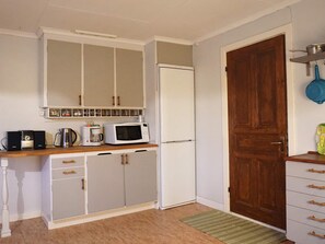 A compact kitchen with white cabinets, a microwave, a coffee maker, and a refrigerator. - 4 Person Holiday Home in Lur (Lur)