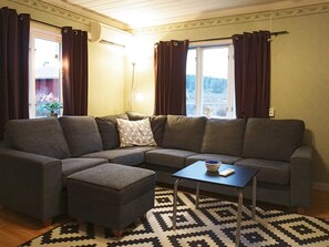 A living room with a sectional sofa, an ottoman, a small table, and a patterned rug. - 4 Person Holiday Home in Lur (Lur)