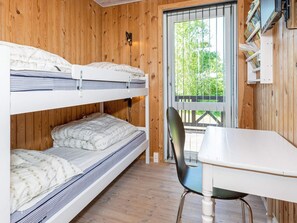 A bunk bed room with a table and chair, wooden walls, and a window with a view of greenery. - 10 Person Holiday Home in Logstor (Logstor)