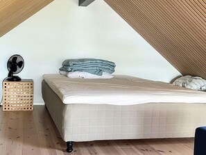 Une chambre à coucher avec un lit, un ventilateur et une caisse en bois.