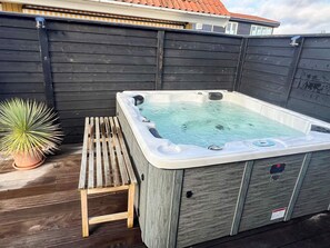 A hot tub with a wooden bench, a potted plant, and a wooden fence. - 6 Person Holiday Home in Otterup (Otterup)
