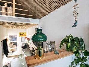 A room with a wooden ceiling, a green lamp, a shelf with a plant, and a sign that reads 'Sweets Chocolate'. - 6 Person Holiday Home in Otterup (Otterup)