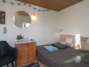A bedroom with a bed, a dresser, a chair, a mirror, and string lights. - 6 Person Holiday Home in Otterup (Otterup)