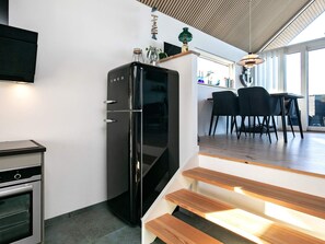 A modern kitchen with a built-in refrigerator, a stove, and a dining area with chairs and a table. - 6 Person Holiday Home in Otterup (Otterup)
