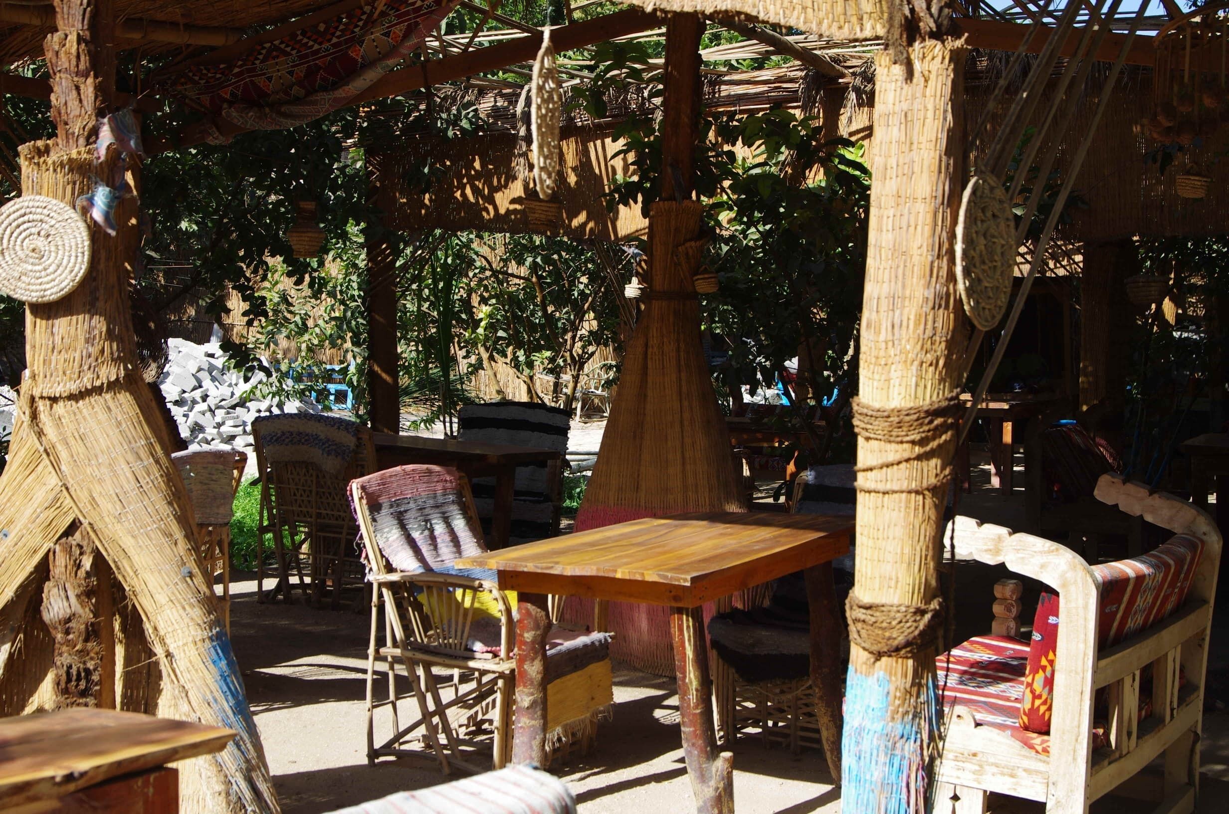 A rustic outdoor seating area with woven furniture and a thatched roof structure.