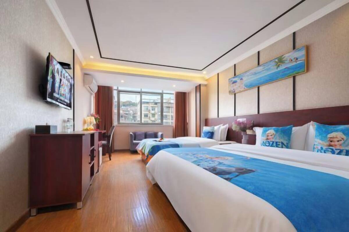 Una habitación de hotel con una cama grande, un escritorio, un televisor y una ventana con vistas a la ciudad.