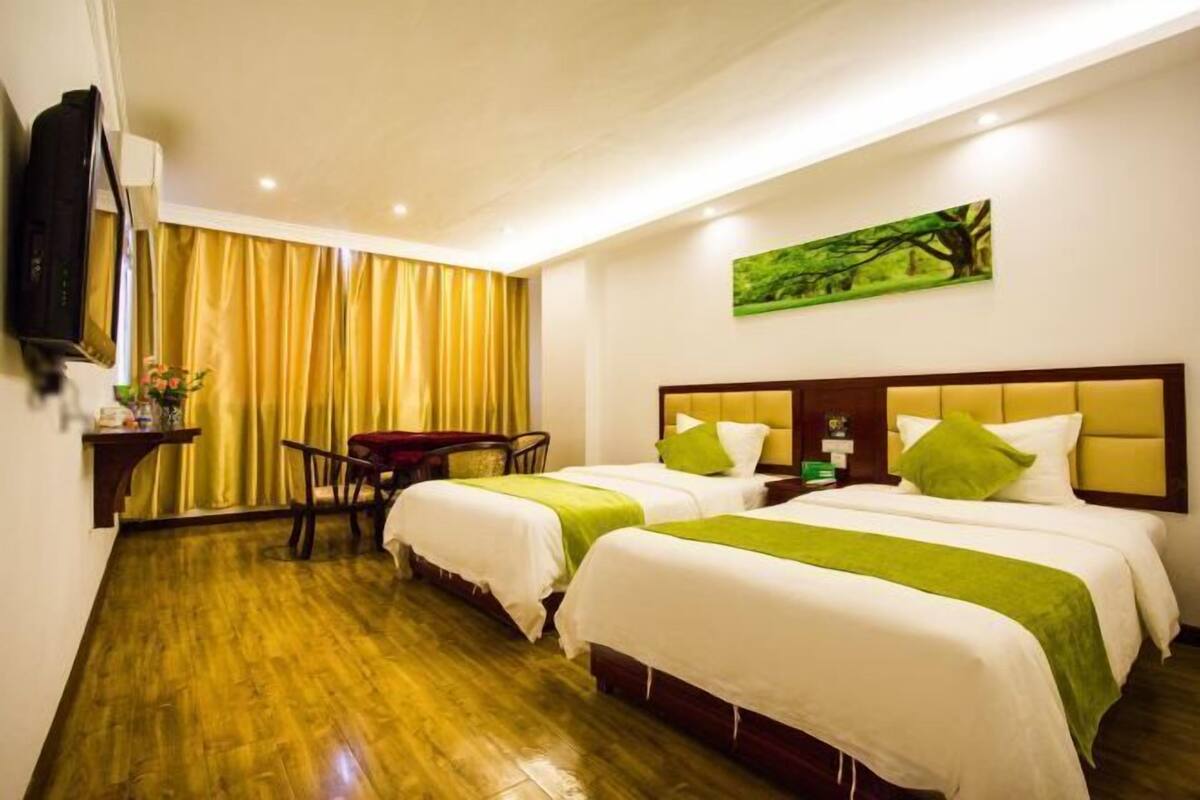 Habitación de hotel con dos camas, televisor, escritorio y un cuadro en la pared.