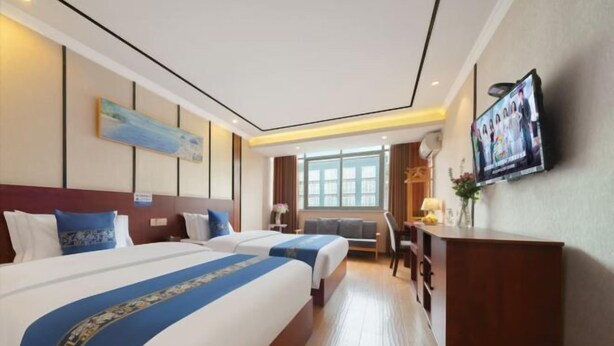 A hotel room with two beds, a desk, a TV, and a window. - Dongyulou Hotel (Jishou University Zhangjiajie Campus) (Zhangjiajie)