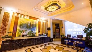 A hotel reception area with a marble counter, a large digital screen displaying text, and a ceiling with a unique light fixture. - Dongyulou Hotel (Jishou University Zhangjiajie Campus) (Zhangjiajie)