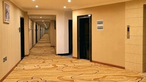 A hotel corridor with a patterned carpet, doors, and recessed lighting. - Dongyulou Hotel (Jishou University Zhangjiajie Campus) (Zhangjiajie)