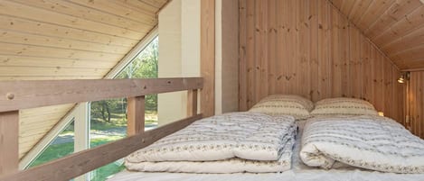 A bedroom with a wooden ceiling, a bed with multiple pillows, and a window.